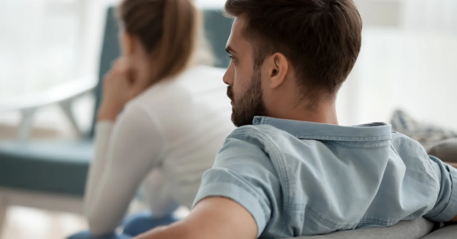 A couple sitting together yet appearing emotionally distant, highlighting how to know if a partner is emotionally una...