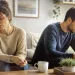 Couple looking distant while engaging in separate activities amidst a chaotic environment
