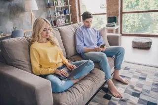 A person looking thoughtfully at a phone, pondering AI's effect on real relationships