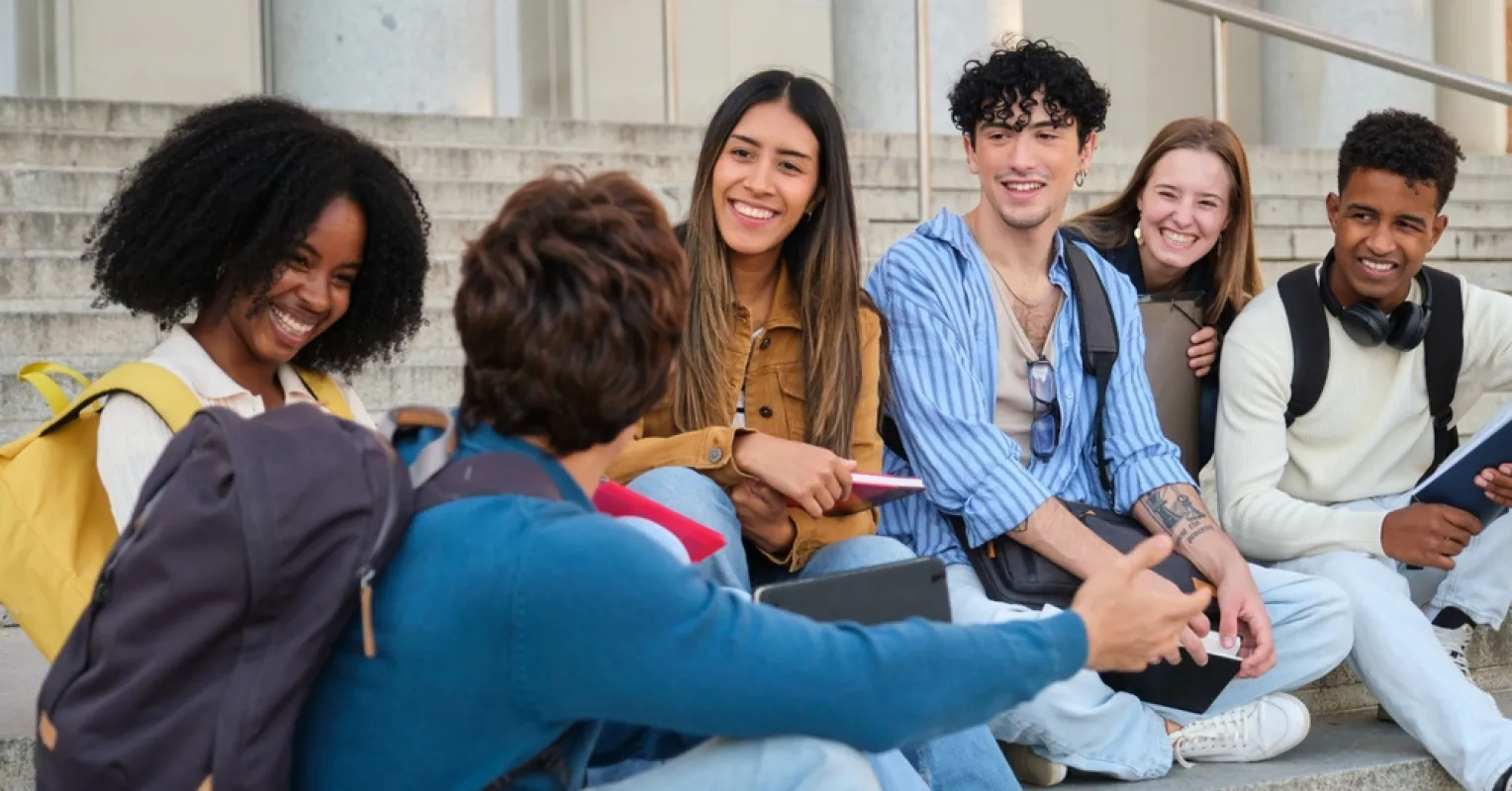 A group of friends laughing together, while one person appears left out and reflective.