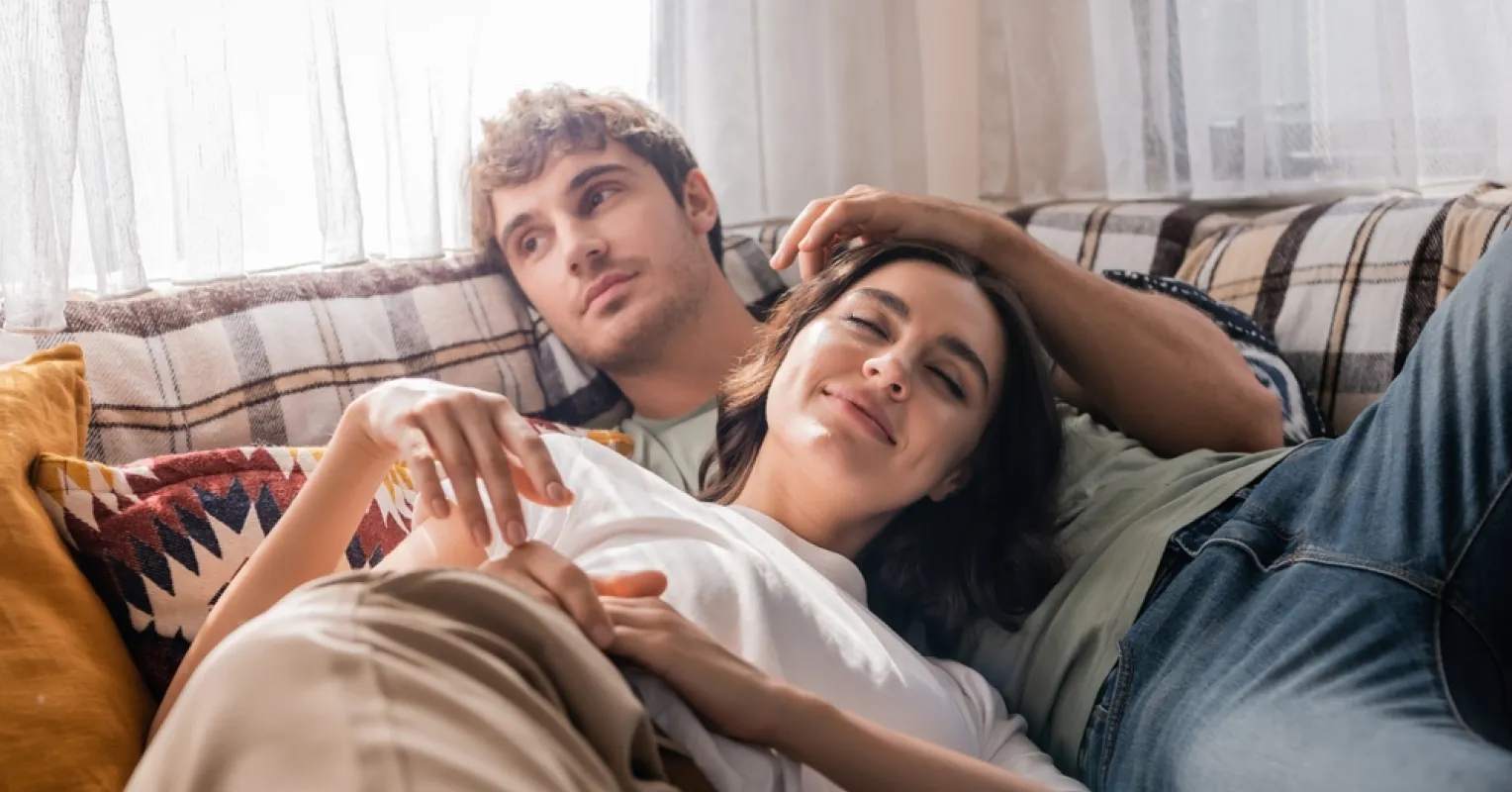 Couple sitting together, one partner uncertain while avoiding serious conversations