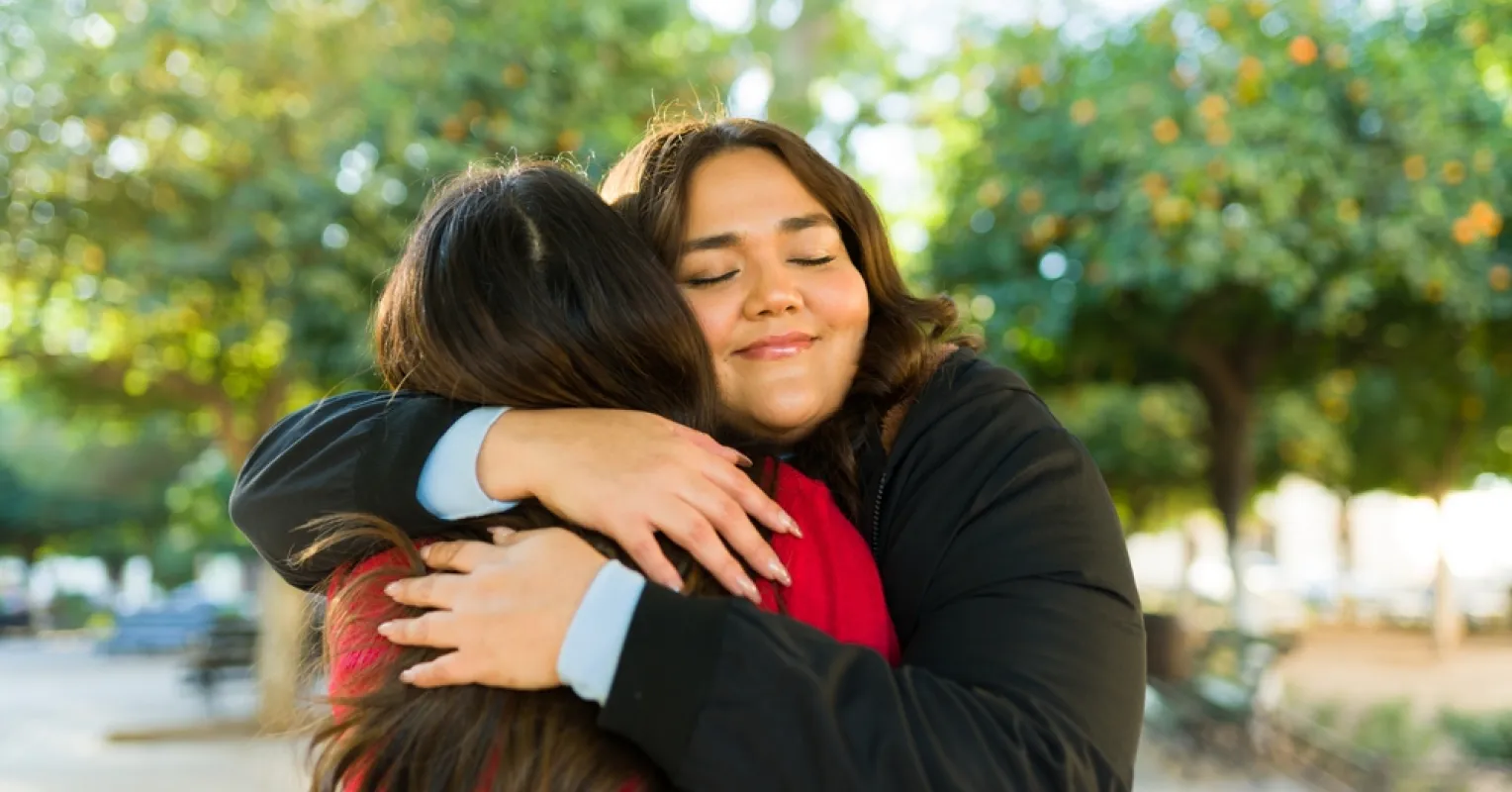 Two people sharing a warm hug at their first meeting, expressing relationship signals through body language.