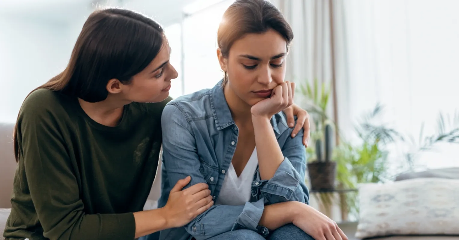 Person feeling overwhelmed while receiving a call from a friend seeking support.