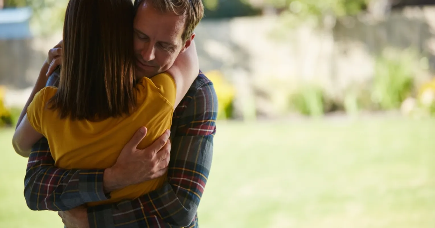 Person standing with arms crossed, showing discomfort in a social situation involving hugs