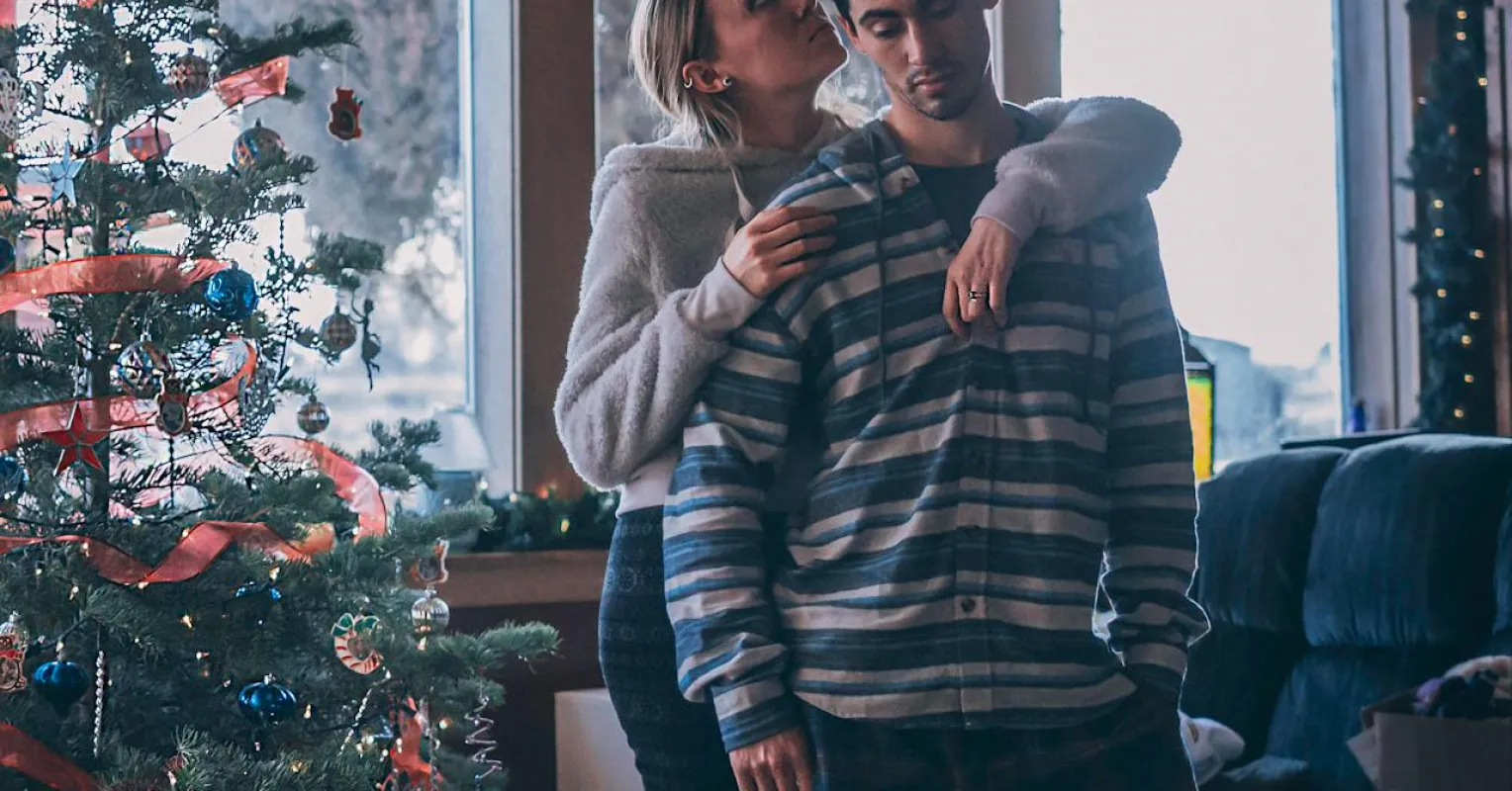 Couple sitting apart, one looking thoughtful, showing emotional distance during holidays