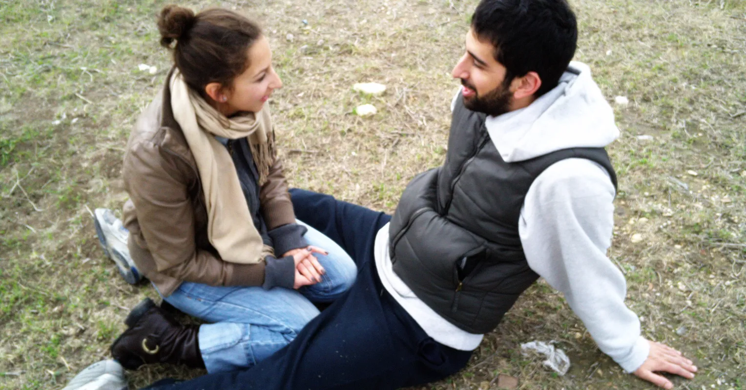 Couple sitting together but looking distant, struggling to open up emotionally