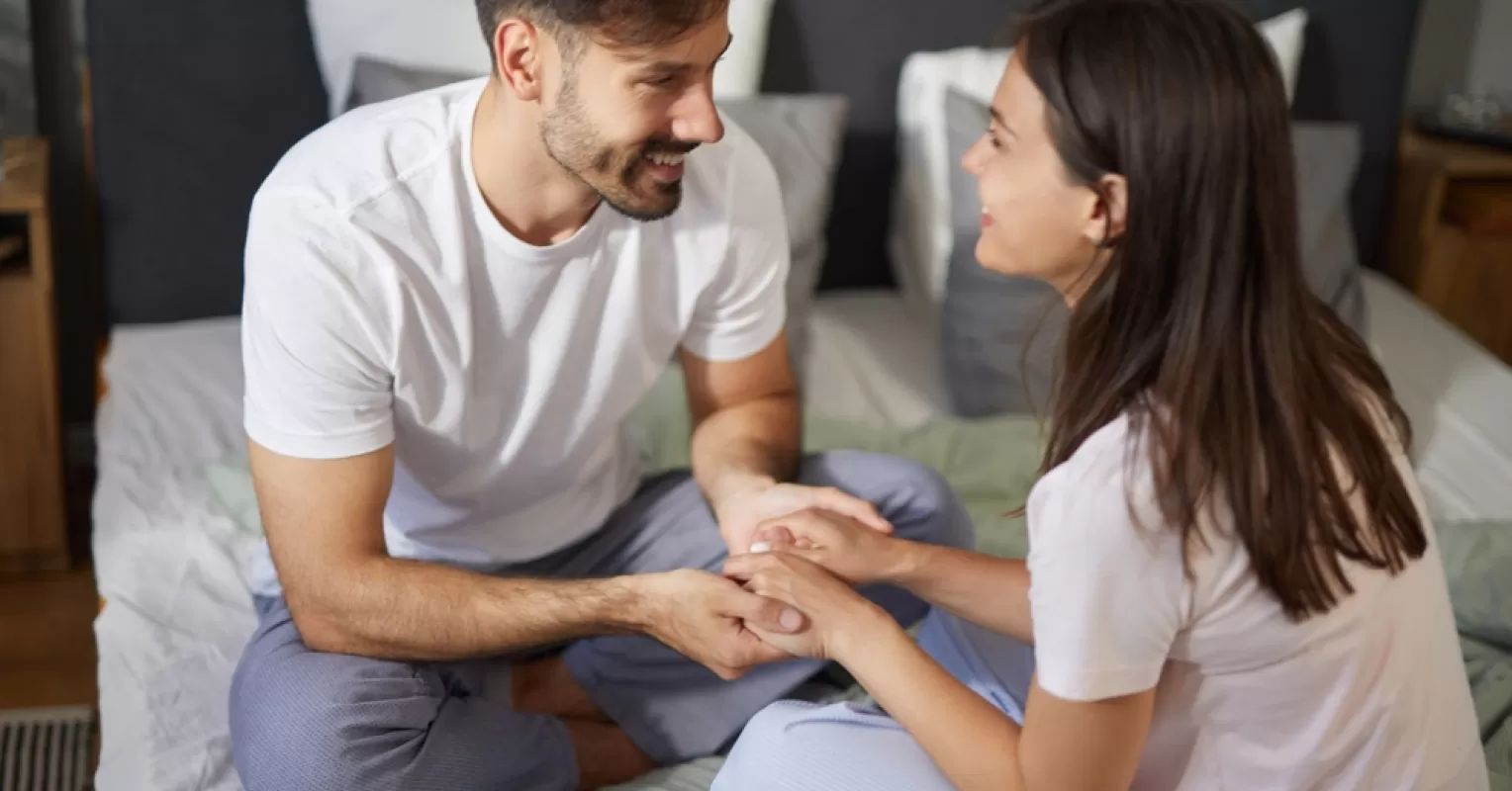 Couple sitting comfortably together, discussing their needs around scheduling intimacy with ease