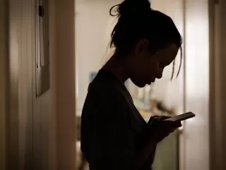 A person anxiously checking their phone, concerned about their partner's digital behavior.