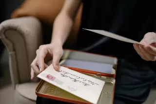 Person hesitating while writing a letter, showing vulnerability in expressing feelings