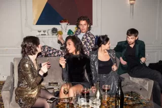 Group of friends laughing together, yet one appears visibly tired from socializing