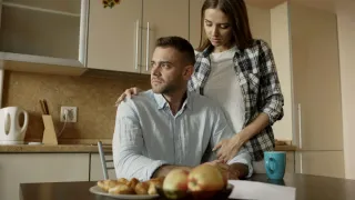 Couple discussing finances while one partner shows signs of anxiety and concern