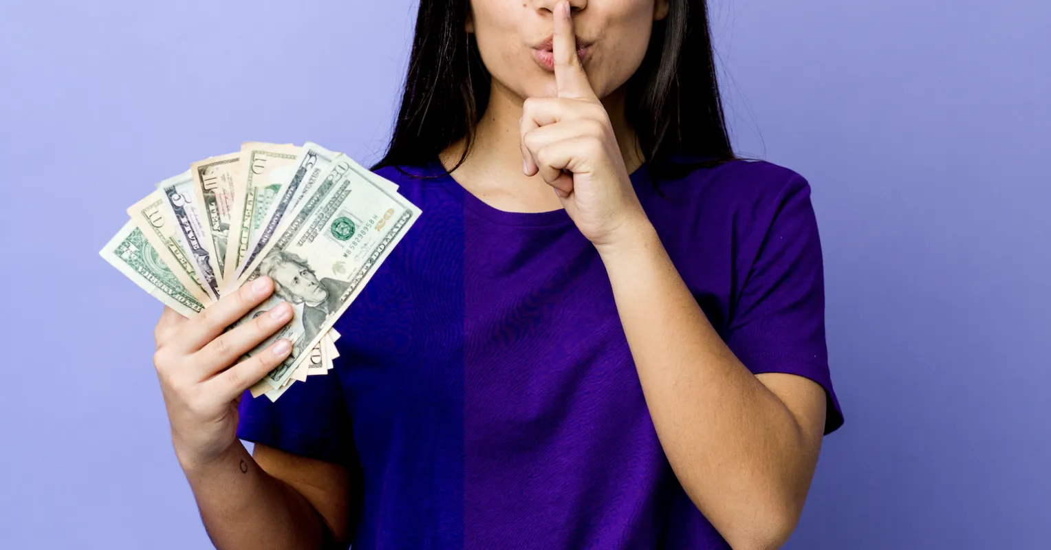 Couple sitting silently at a table, one partner avoiding eye contact during financial discussion.