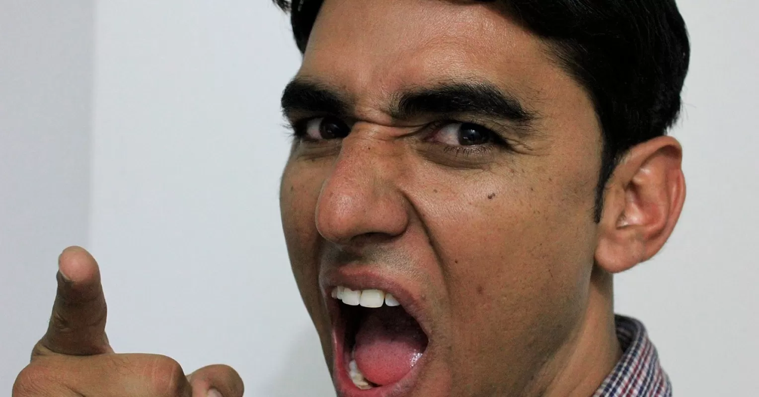 Man experiencing anger while avoiding discussion of deeper feelings during a conversation