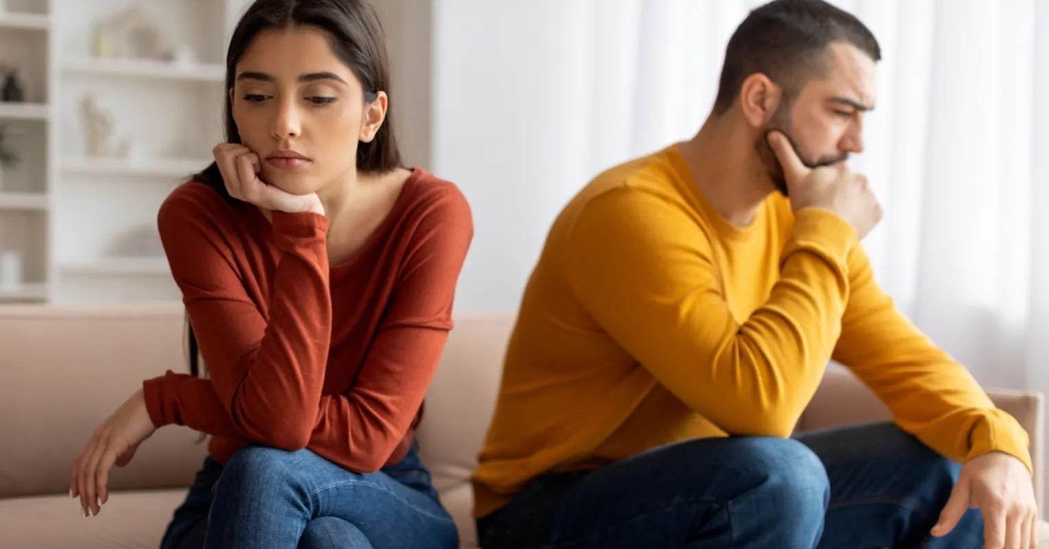 Couple discussing finances while showing signs of anxiety and mixed emotions