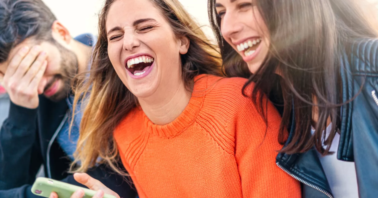 Group of friends laughing, while one looks left out and confused about inside jokes