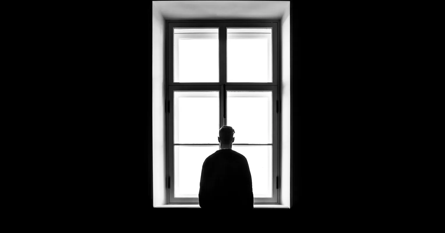 A person sitting alone in a crowded space, reflecting on how loneliness affects physical health