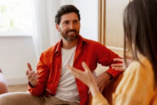 Couple sitting together, one partner appears distant while verbally accessing their feelings