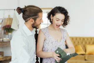 A person awkwardly smiling while holding an unwanted gift during a gathering, reflecting relationship signals.