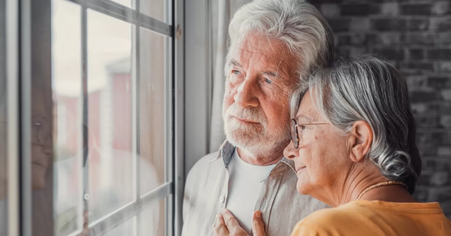 A grandparent gazing longingly at family photos, reflecting on estrangement from their grandchildren