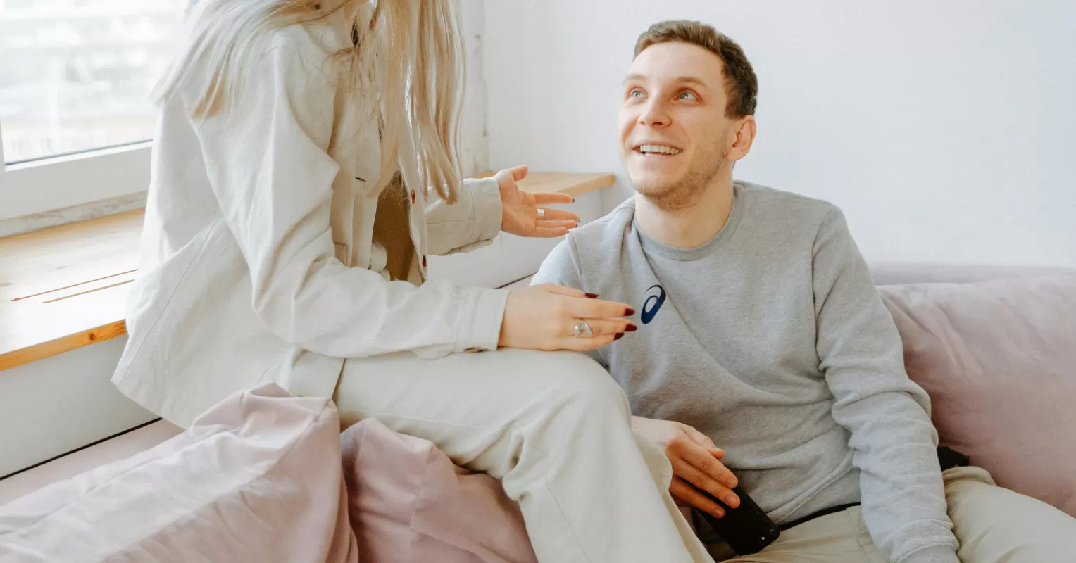 Couple sitting in silence, one looking contemplative about hesitation in expressing feelings
