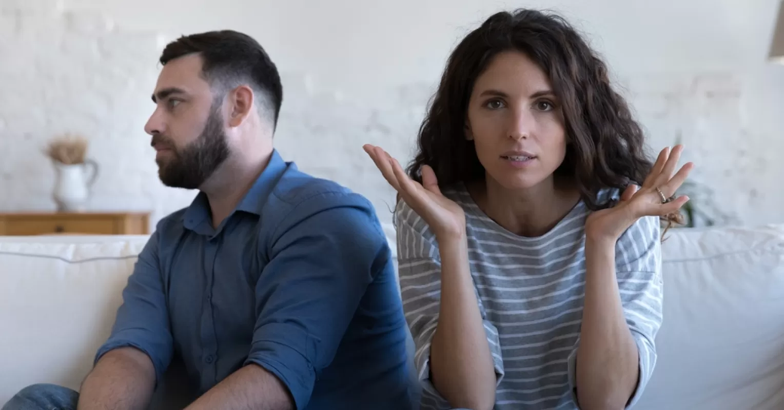 Couple facing each other with expressions of frustration and resentment about entitlement issues