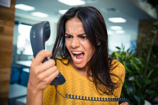A person using calming gestures to soothe an angry friend during a heated discussion