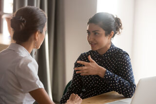 Two people sharing a laugh, illustrating how to engage someone in a conversation
